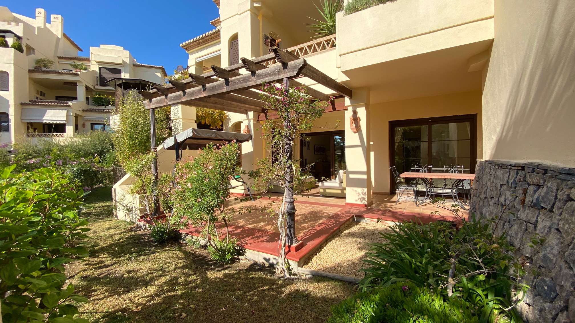 Appartement avec jardin dans le complexe de Villa Gadea. Il y a deux chambres et une terrasse avec beaucoup de plantes.